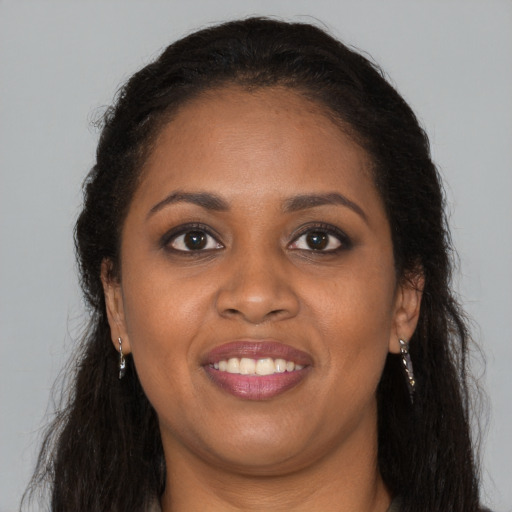 Joyful black young-adult female with long  brown hair and brown eyes