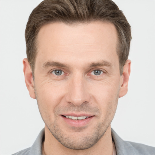 Joyful white young-adult male with short  brown hair and grey eyes