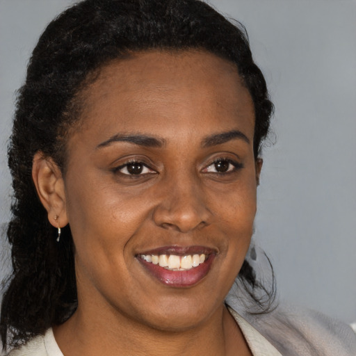 Joyful black young-adult female with long  brown hair and brown eyes