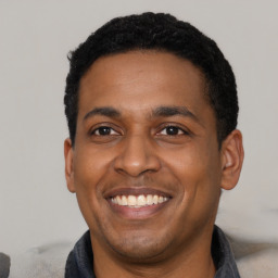 Joyful latino young-adult male with short  black hair and brown eyes