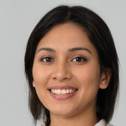 Joyful latino young-adult female with long  brown hair and brown eyes