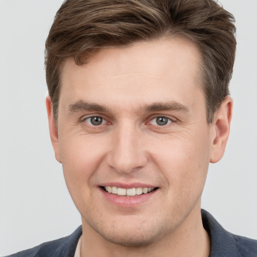 Joyful white young-adult male with short  brown hair and grey eyes