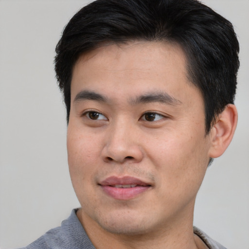 Joyful asian young-adult male with short  brown hair and brown eyes