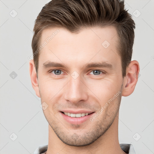 Joyful white young-adult male with short  brown hair and grey eyes