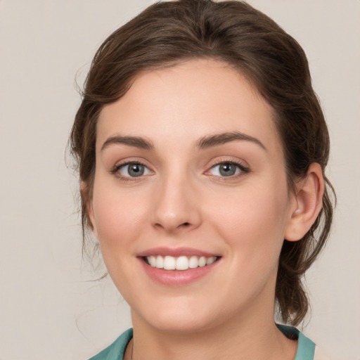 Joyful white young-adult female with medium  brown hair and green eyes