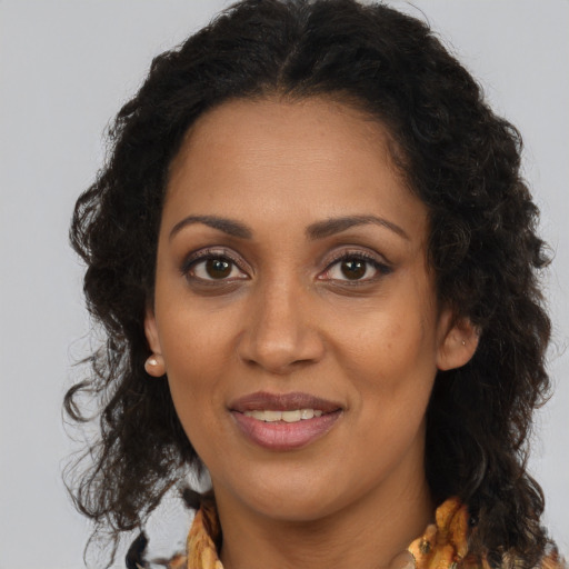 Joyful black young-adult female with long  brown hair and brown eyes