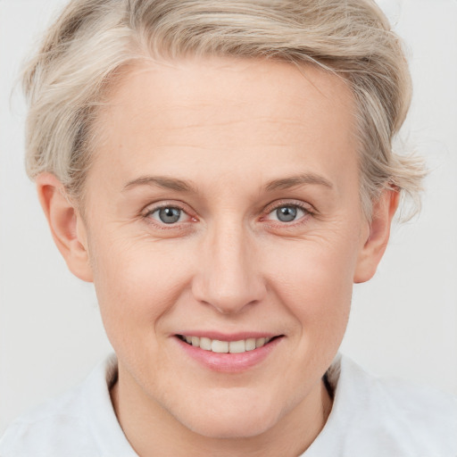 Joyful white adult female with short  blond hair and blue eyes