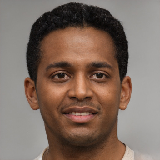 Joyful black young-adult male with short  brown hair and brown eyes