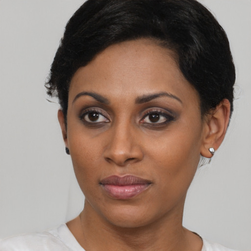 Joyful black young-adult female with short  black hair and brown eyes