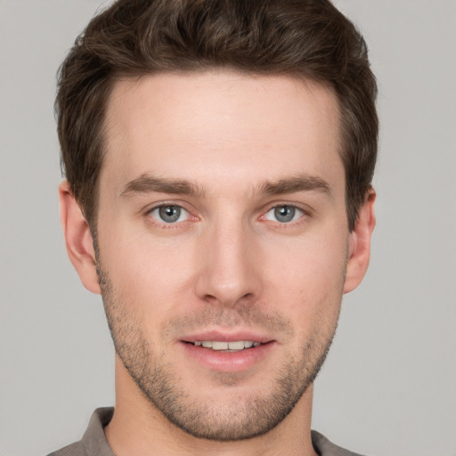 Joyful white young-adult male with short  brown hair and grey eyes