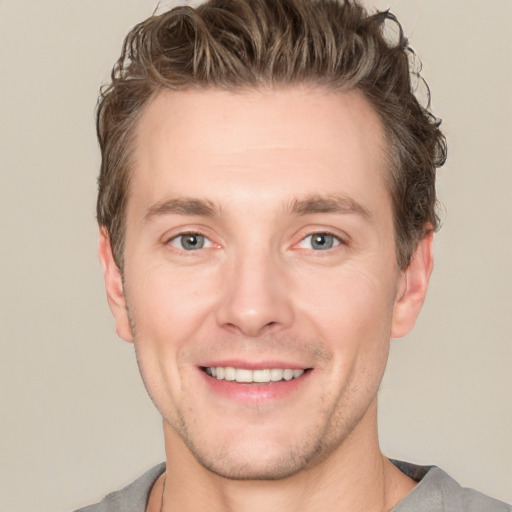 Joyful white young-adult male with short  brown hair and grey eyes