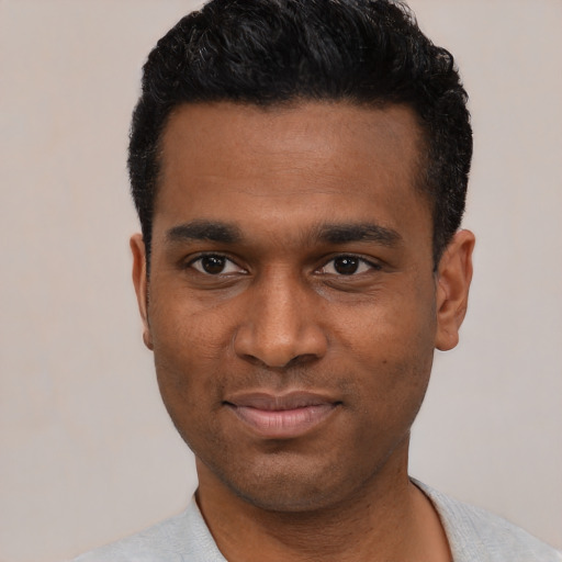Joyful black young-adult male with short  black hair and brown eyes
