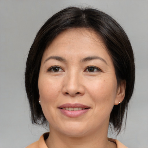 Joyful asian adult female with medium  brown hair and brown eyes