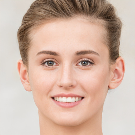 Joyful white young-adult female with short  brown hair and grey eyes