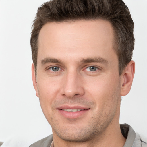 Joyful white young-adult male with short  brown hair and grey eyes