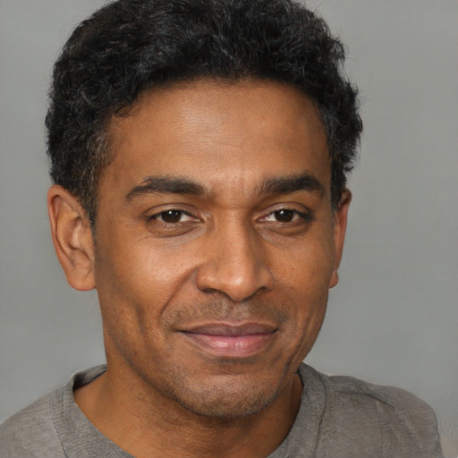 Joyful black adult male with short  brown hair and brown eyes