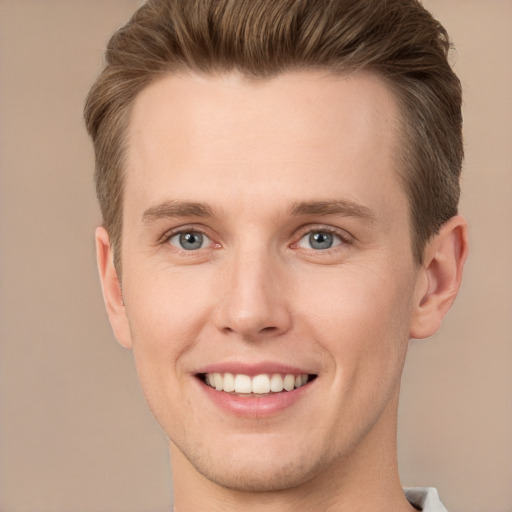 Joyful white young-adult male with short  brown hair and grey eyes