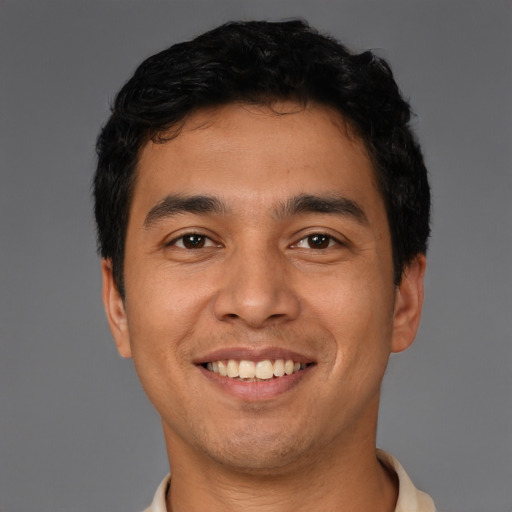 Joyful latino young-adult male with short  black hair and brown eyes