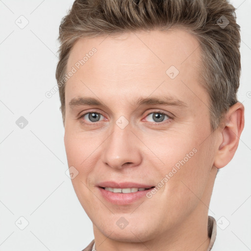 Joyful white young-adult male with short  brown hair and grey eyes