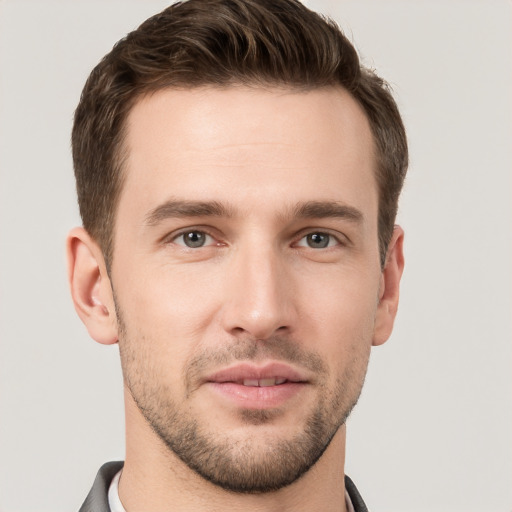 Joyful white young-adult male with short  brown hair and grey eyes