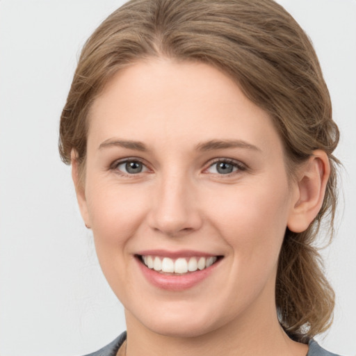 Joyful white young-adult female with medium  brown hair and grey eyes