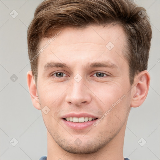 Joyful white young-adult male with short  brown hair and grey eyes