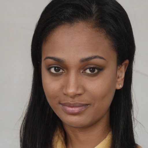 Joyful black young-adult female with long  brown hair and brown eyes