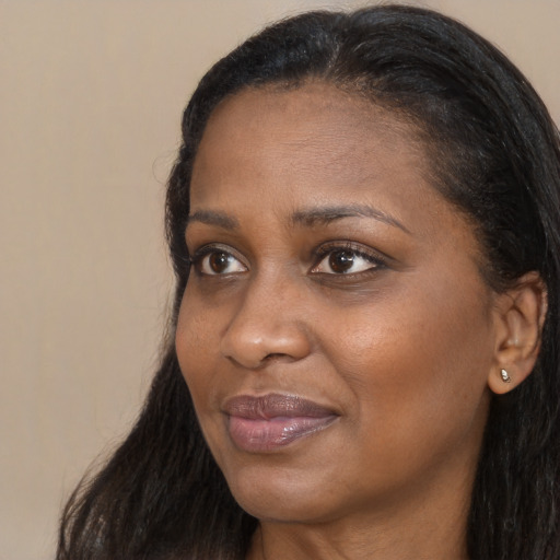 Joyful black adult female with long  brown hair and brown eyes