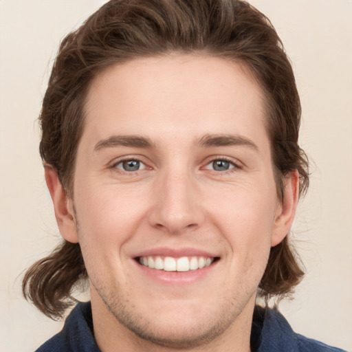 Joyful white young-adult male with medium  brown hair and grey eyes