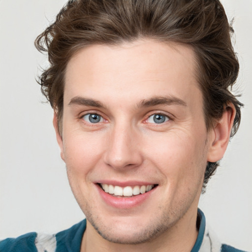 Joyful white young-adult male with short  brown hair and blue eyes