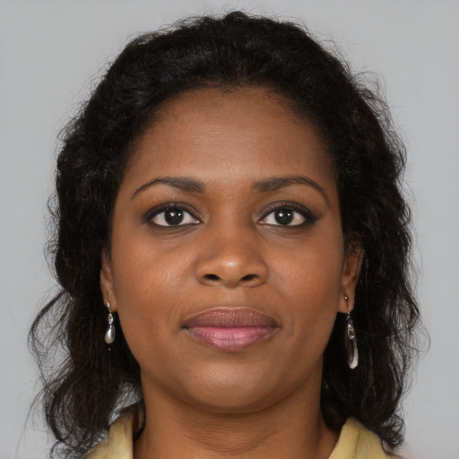 Joyful black young-adult female with long  brown hair and brown eyes