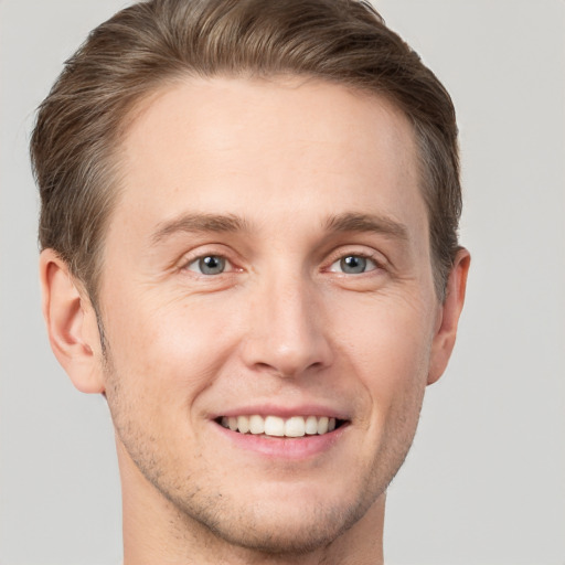 Joyful white young-adult male with short  brown hair and grey eyes