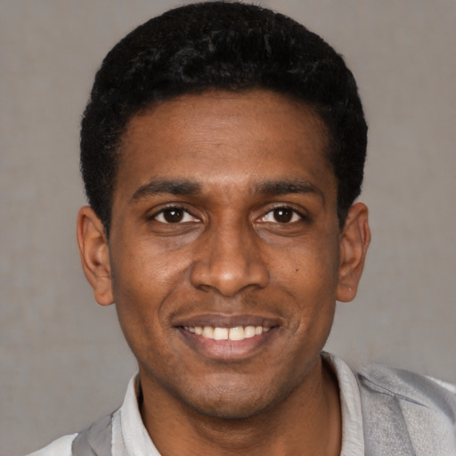 Joyful black young-adult male with short  black hair and brown eyes
