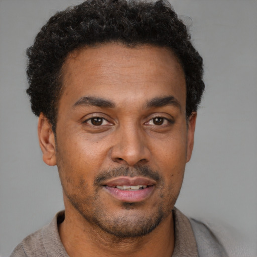 Joyful black young-adult male with short  brown hair and brown eyes