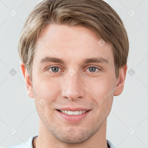 Joyful white young-adult male with short  brown hair and grey eyes