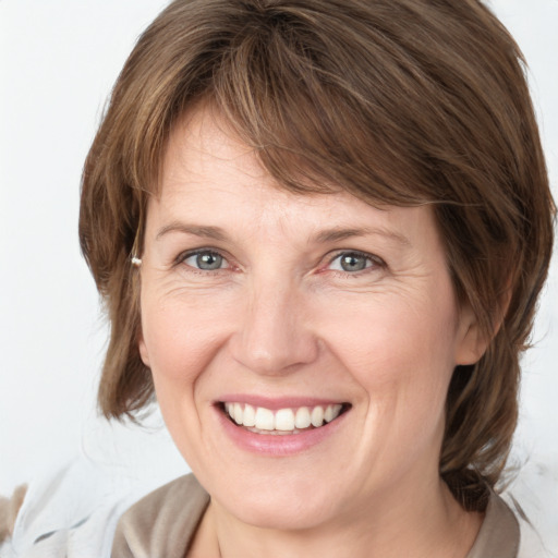 Joyful white adult female with medium  brown hair and grey eyes