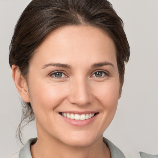 Joyful white young-adult female with medium  brown hair and grey eyes