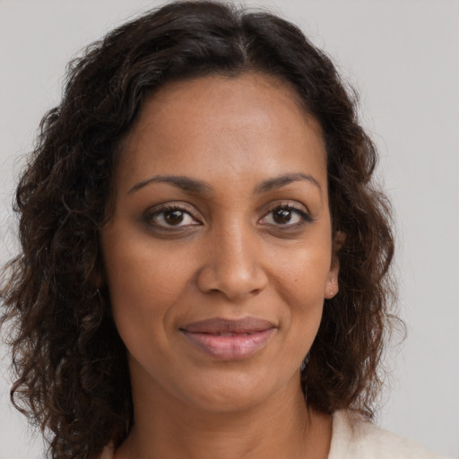 Joyful black young-adult female with long  brown hair and brown eyes
