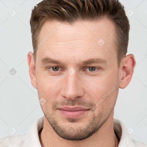 Joyful white young-adult male with short  brown hair and grey eyes