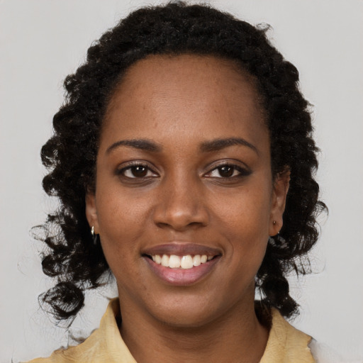 Joyful black young-adult female with long  brown hair and brown eyes
