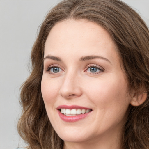 Joyful white young-adult female with long  brown hair and blue eyes