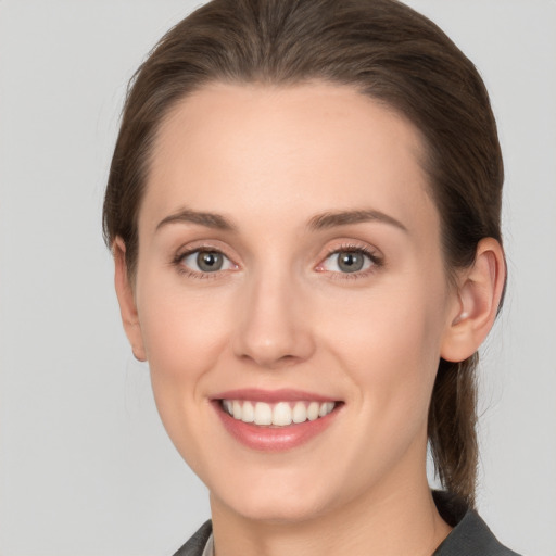 Joyful white young-adult female with medium  brown hair and grey eyes