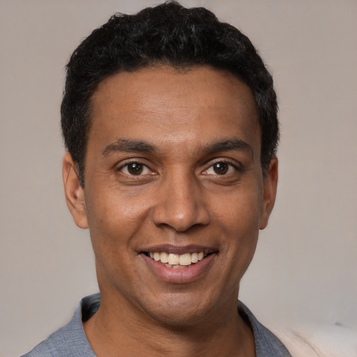 Joyful black young-adult male with short  black hair and brown eyes