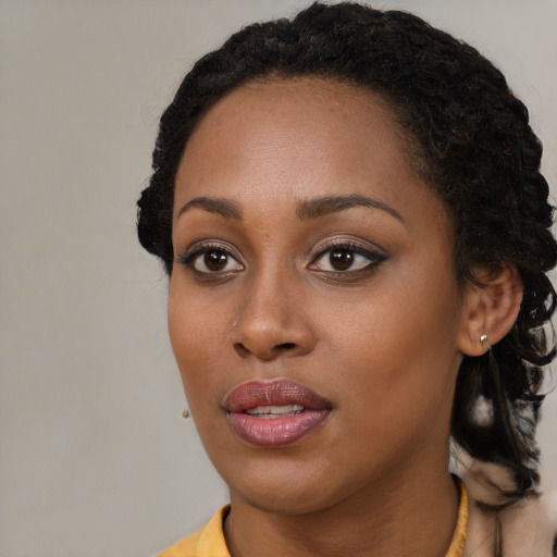 Joyful black young-adult female with long  black hair and brown eyes