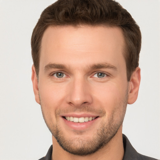 Joyful white young-adult male with short  brown hair and grey eyes