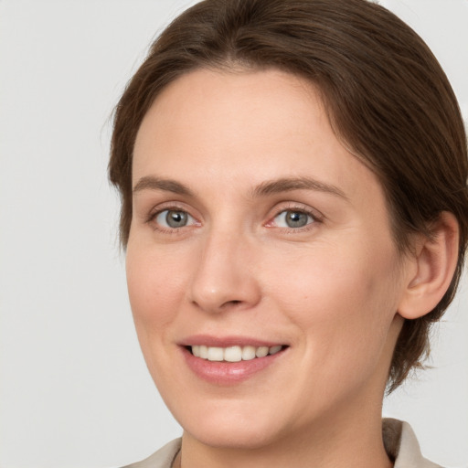 Joyful white young-adult female with medium  brown hair and grey eyes