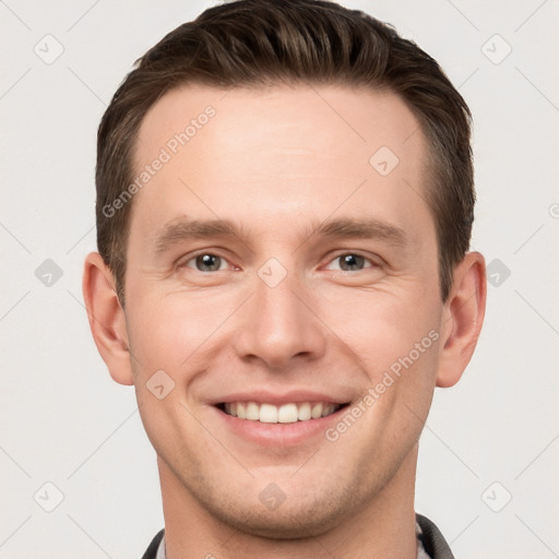 Joyful white young-adult male with short  brown hair and grey eyes