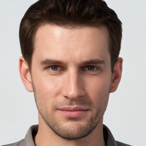 Joyful white young-adult male with short  brown hair and grey eyes