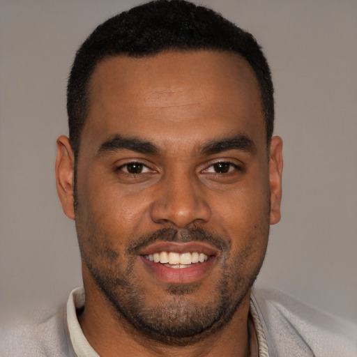 Joyful black young-adult male with short  brown hair and brown eyes