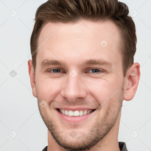 Joyful white young-adult male with short  brown hair and grey eyes